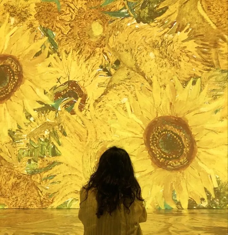 une fille de dos qui regarde un mur de fleurs