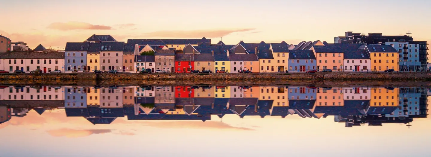 Carte postale montrant les maisons colorées de la ville de Galway se reflétant dans l'eau du port.